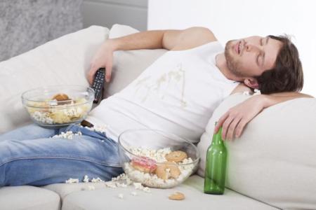 Hombre dormido en sofá con comida y bebida