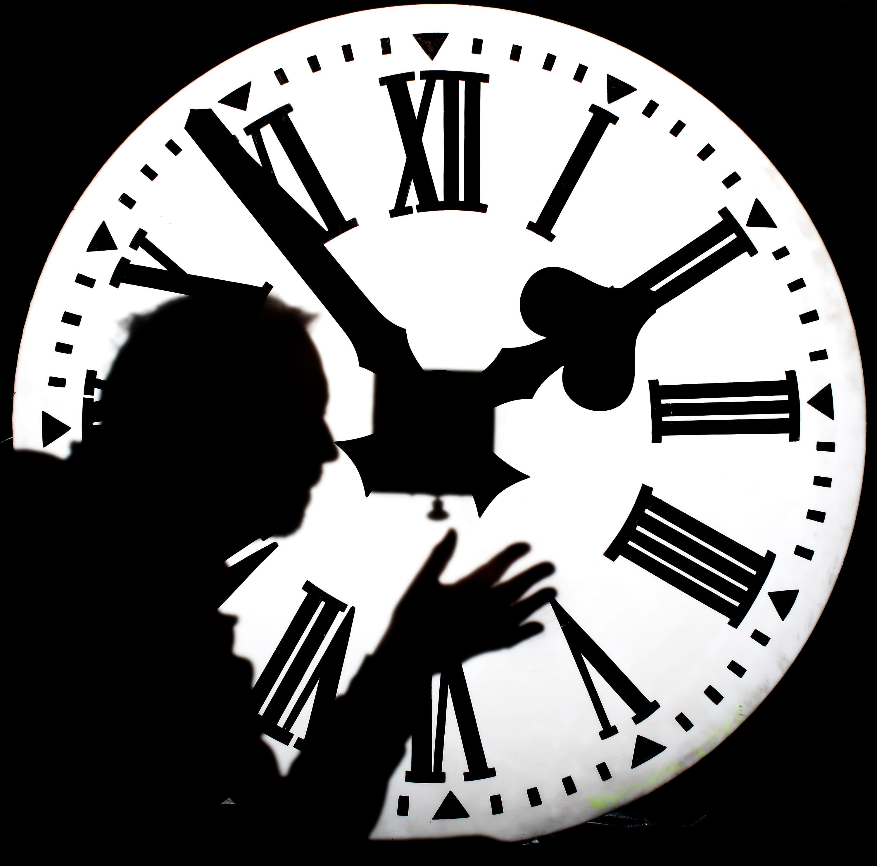 sombra de un hombre frente a un reloj iluminado
